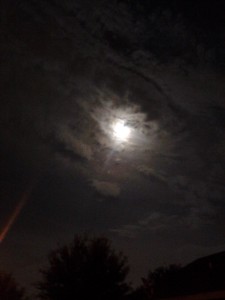 Moonlight shining through cloudy night sky.