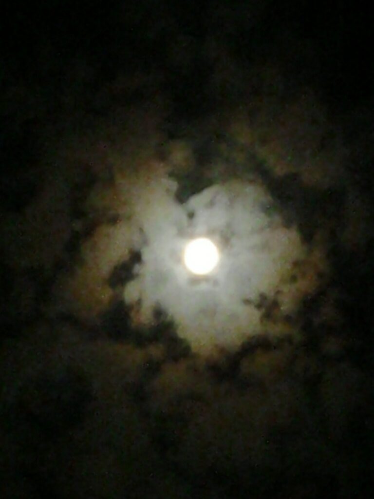 Full moon surrounded by clouds at night.