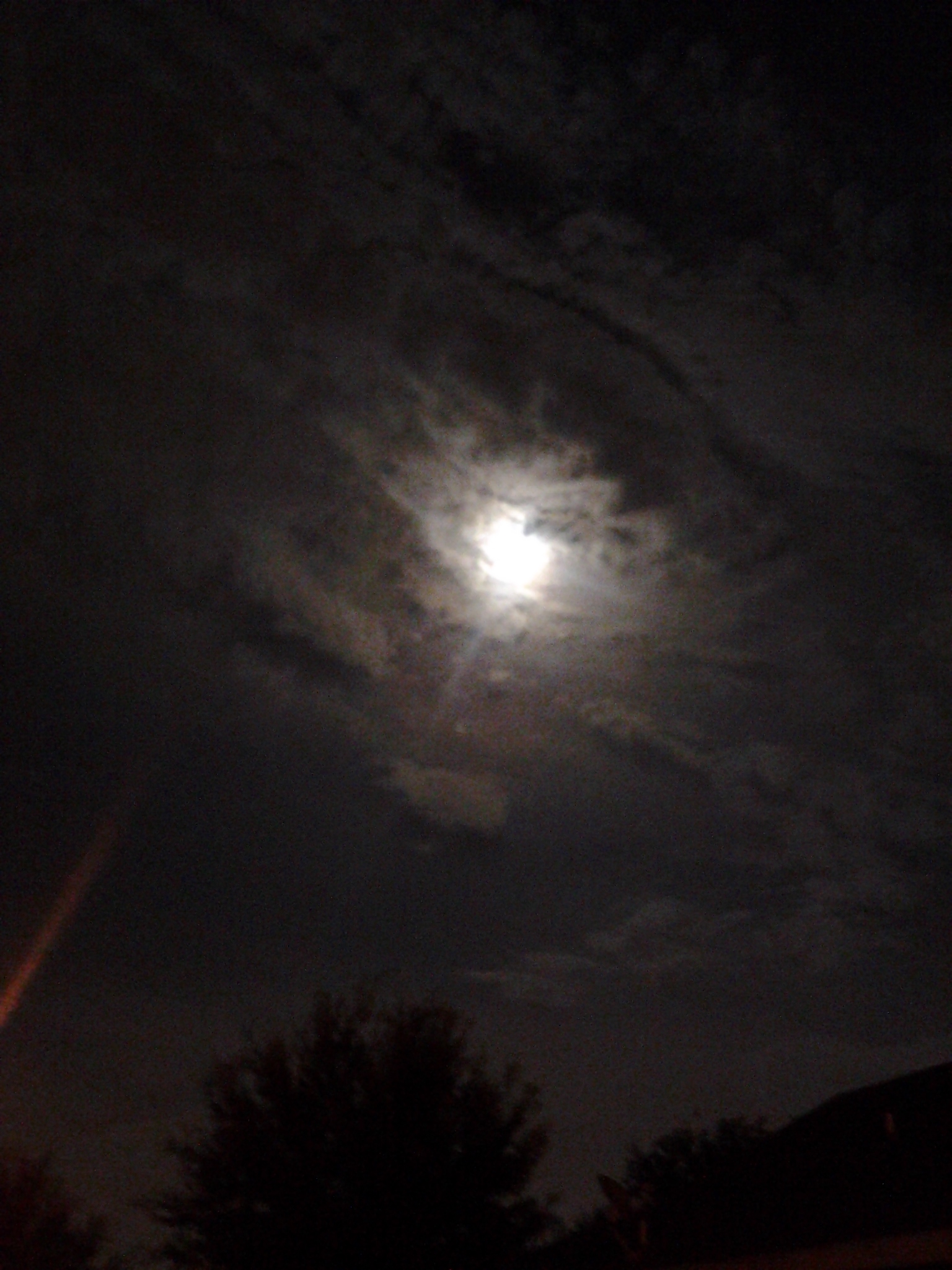 Full moon shining through cloudy night sky.