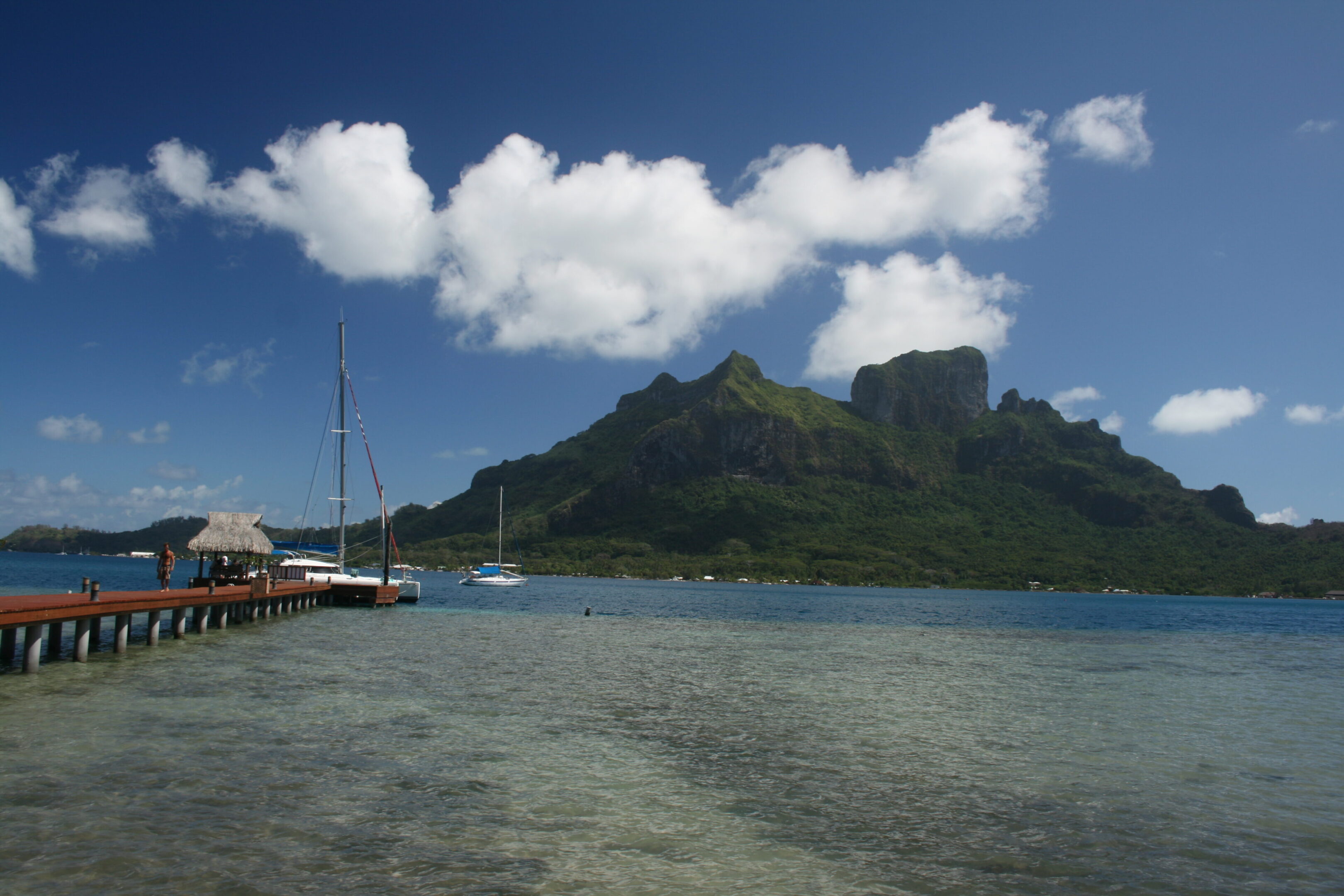 Tropical island with dock and mountain view.