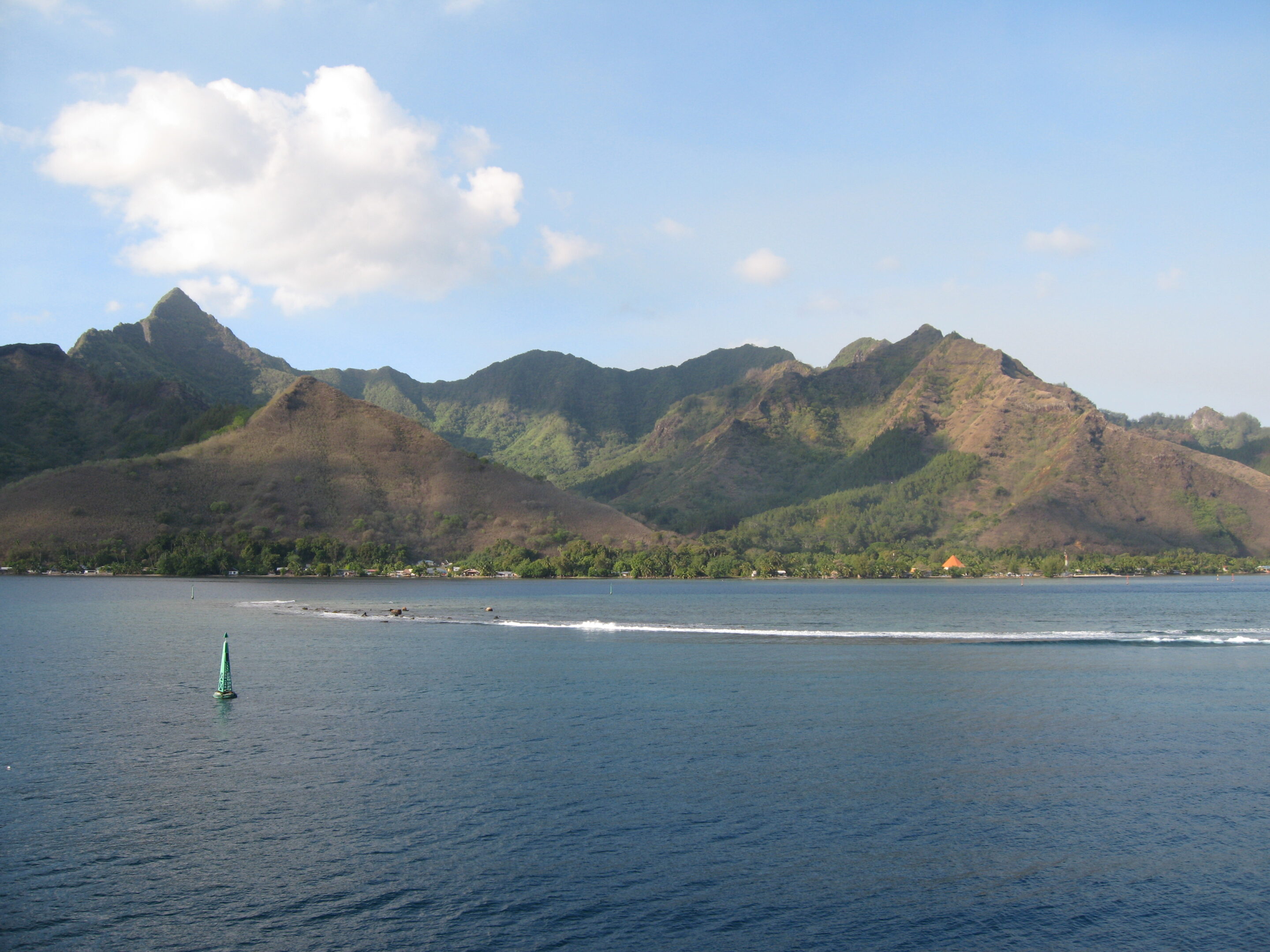 Mountainous coastline with blue sky and water.