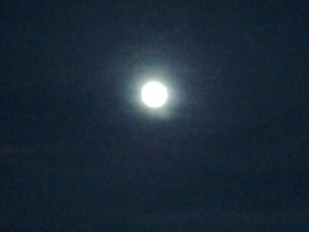 Blurry full moon in dark night sky.