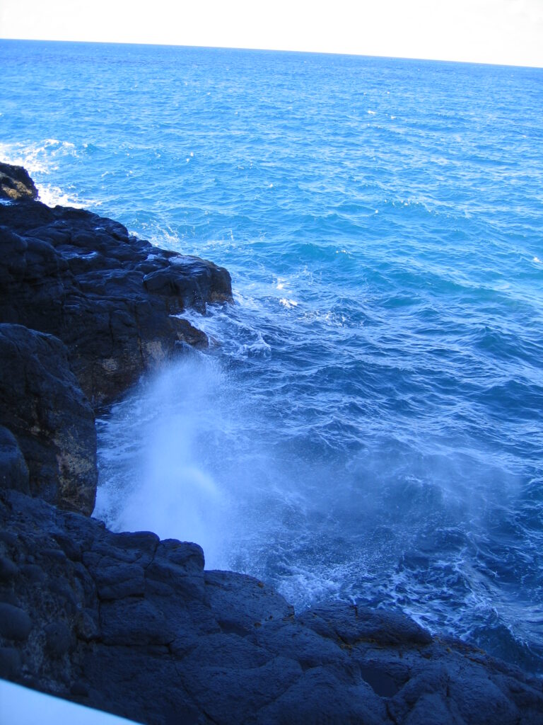 Waves crashing on rocky shoreline with ocean.