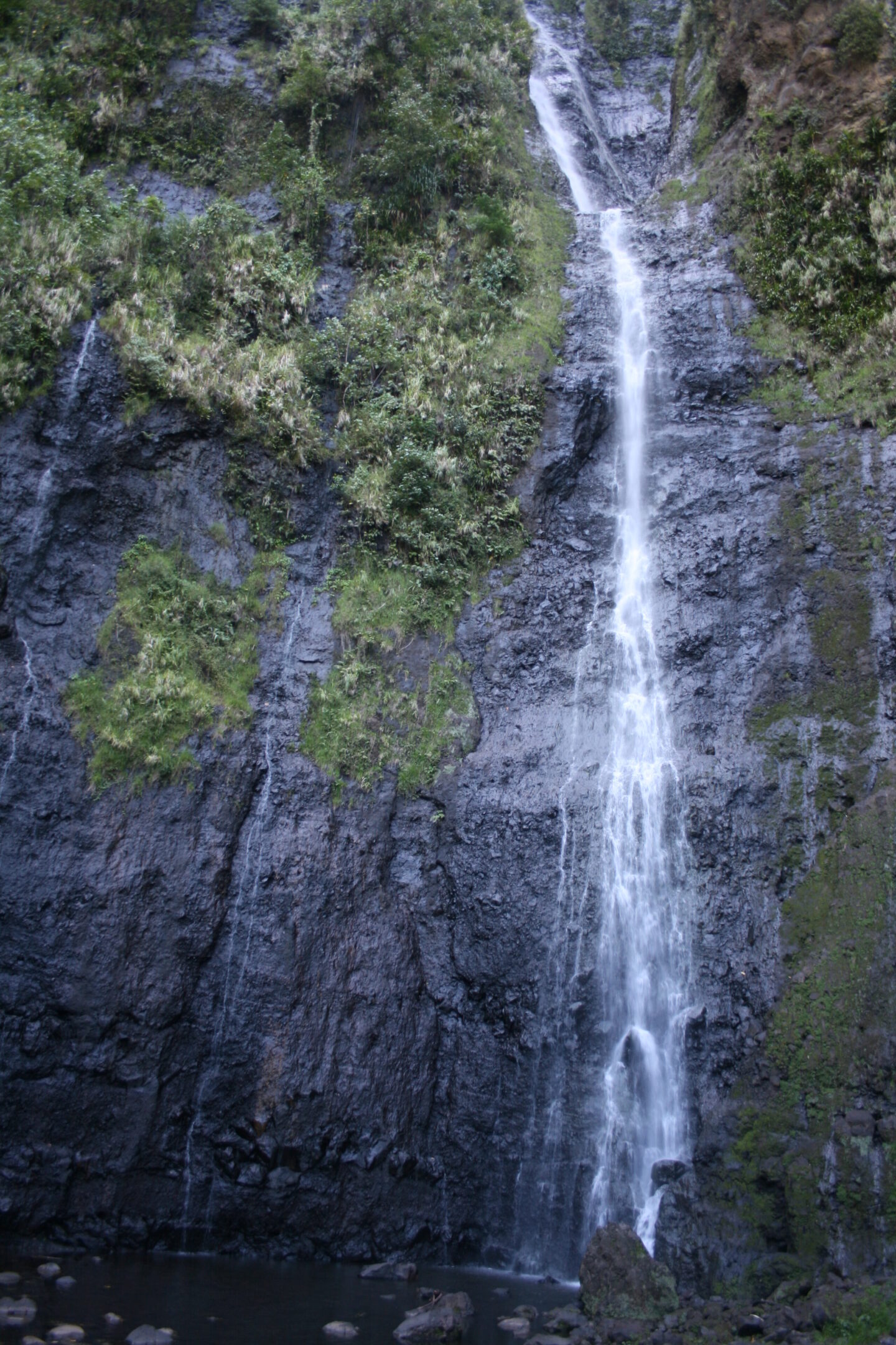Tall waterfall cascading over rocky cliff.