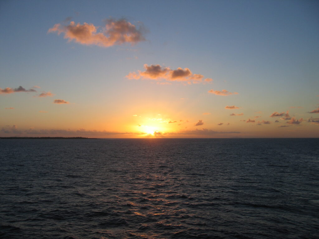 Sunset over the ocean with scattered clouds.