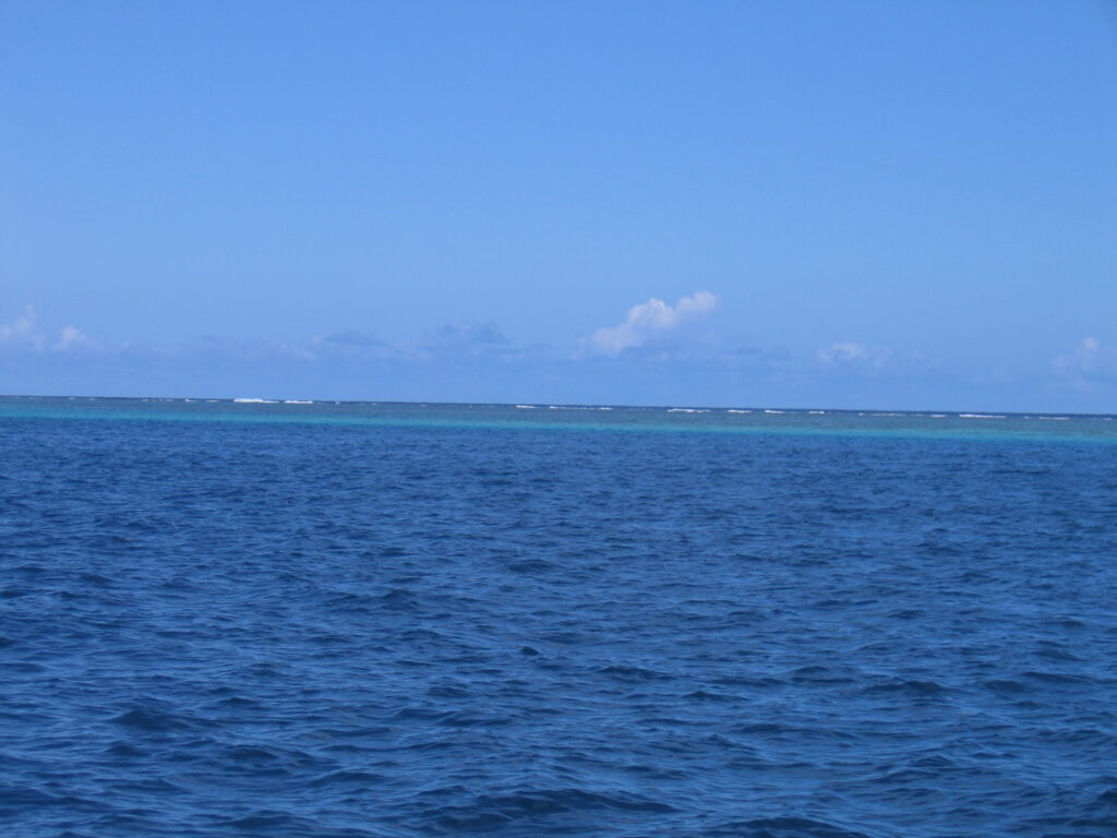 Blue ocean with distant horizon and clouds.