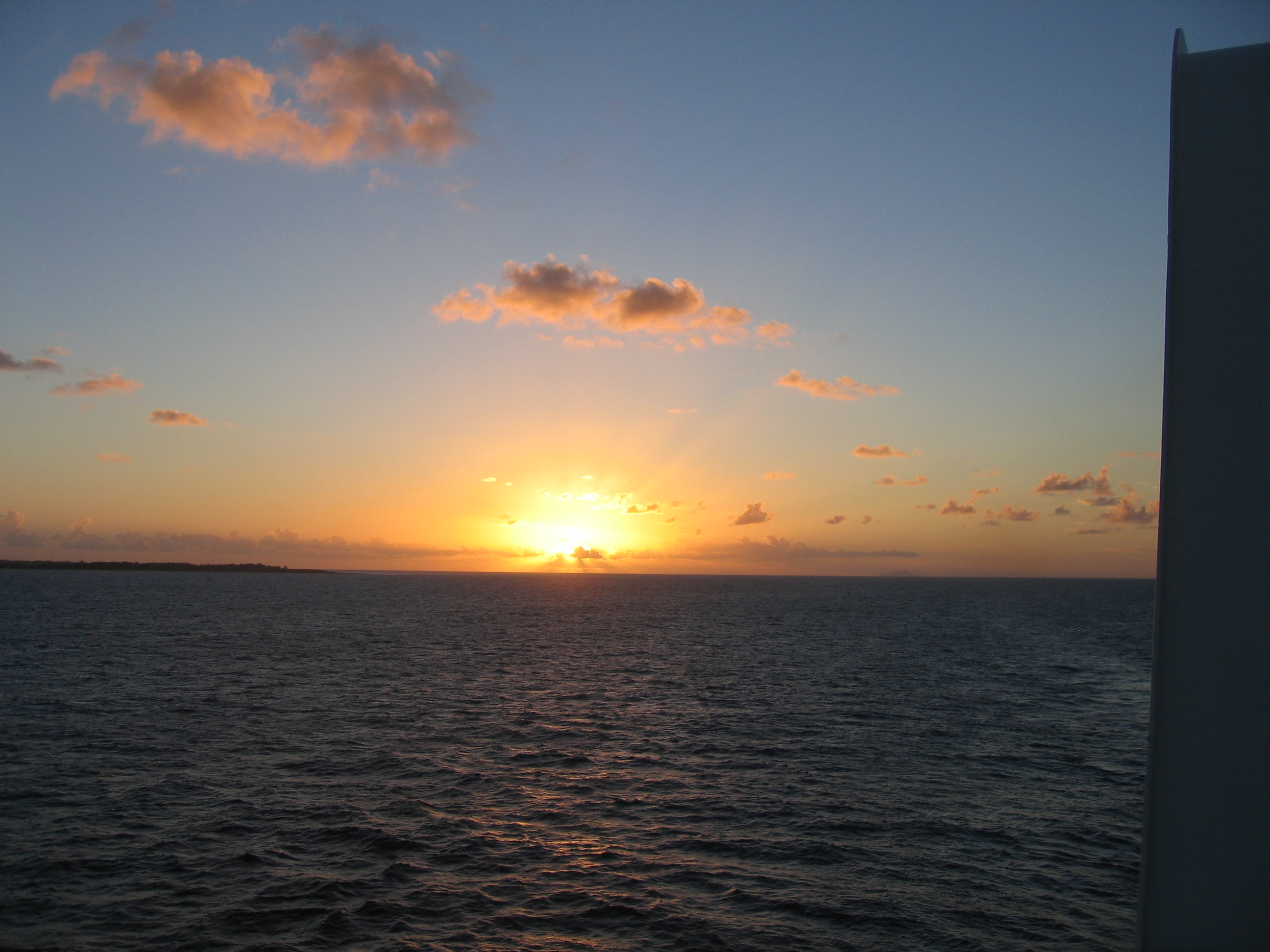 Ocean sunset with scattered clouds.