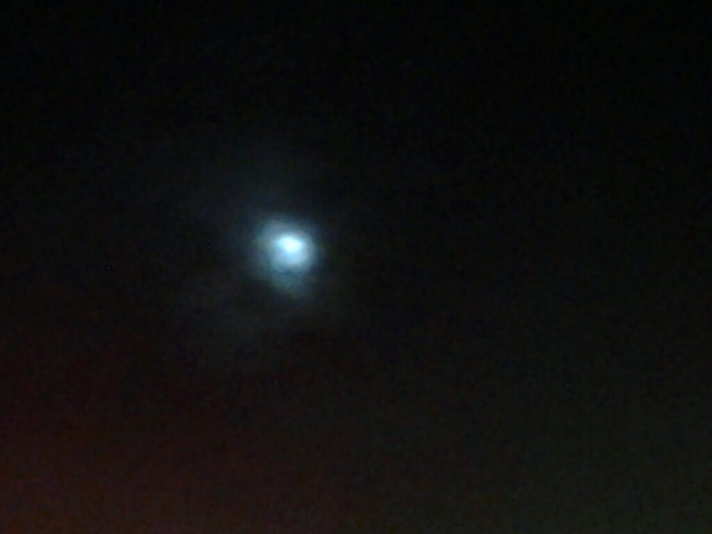 Faint moon in a dark, cloudy sky.