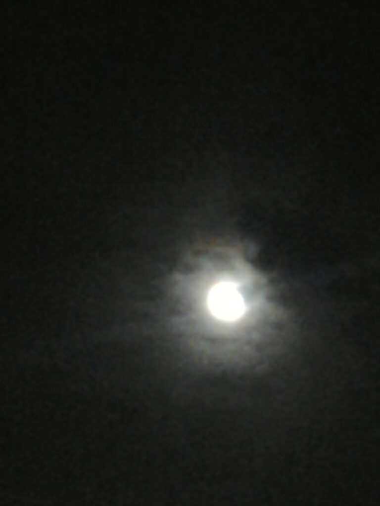 Bright moon surrounded by dark clouds.