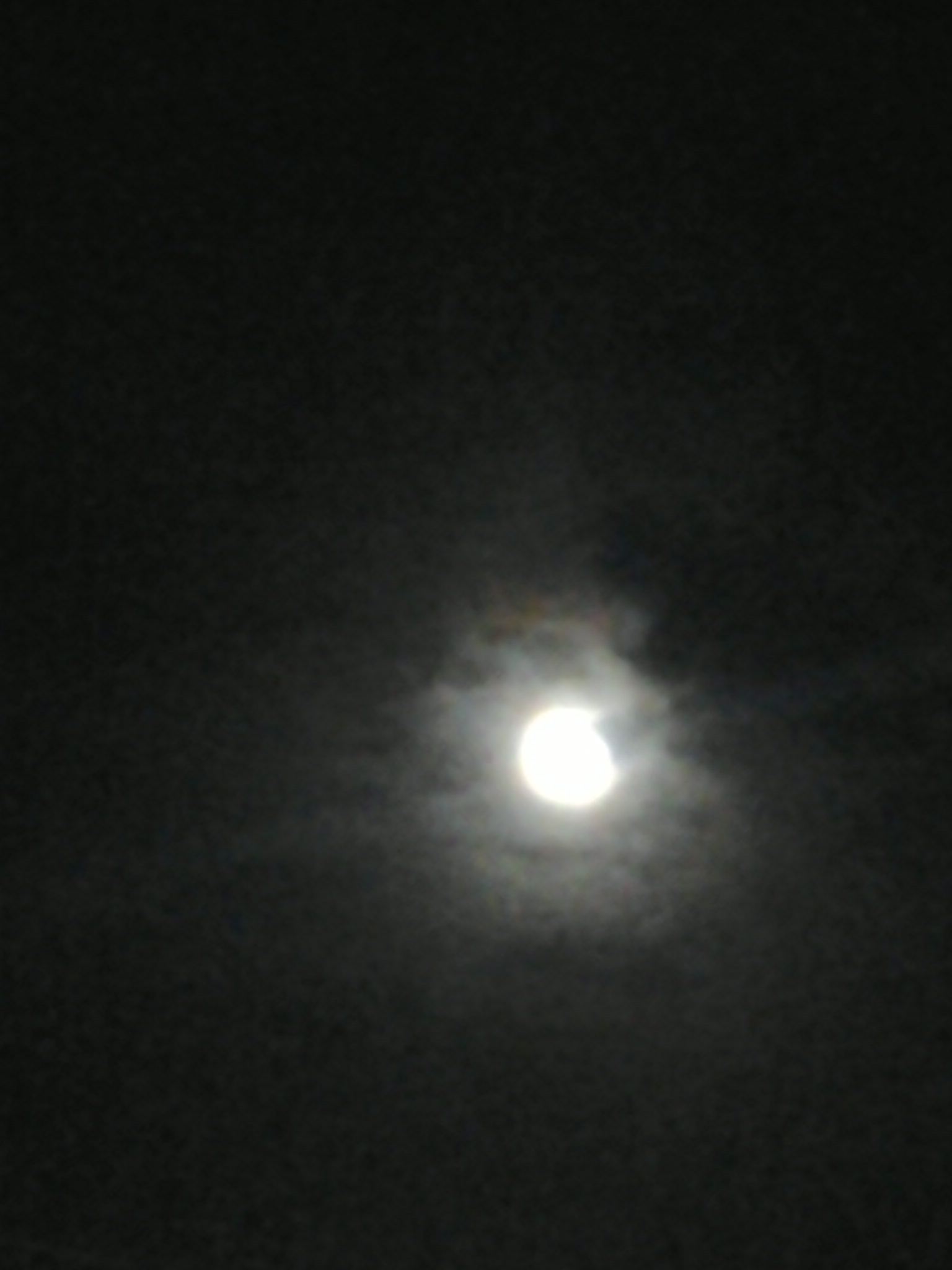 Bright moon surrounded by dark clouds.