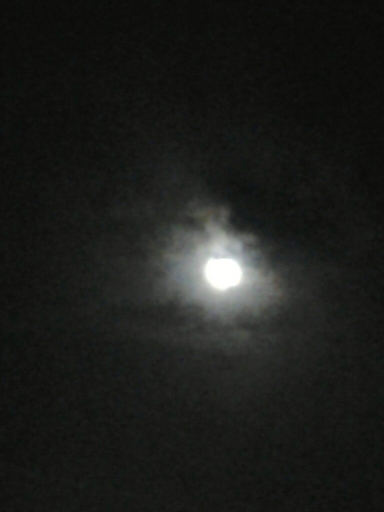Blurry moon in a cloudy night sky.
