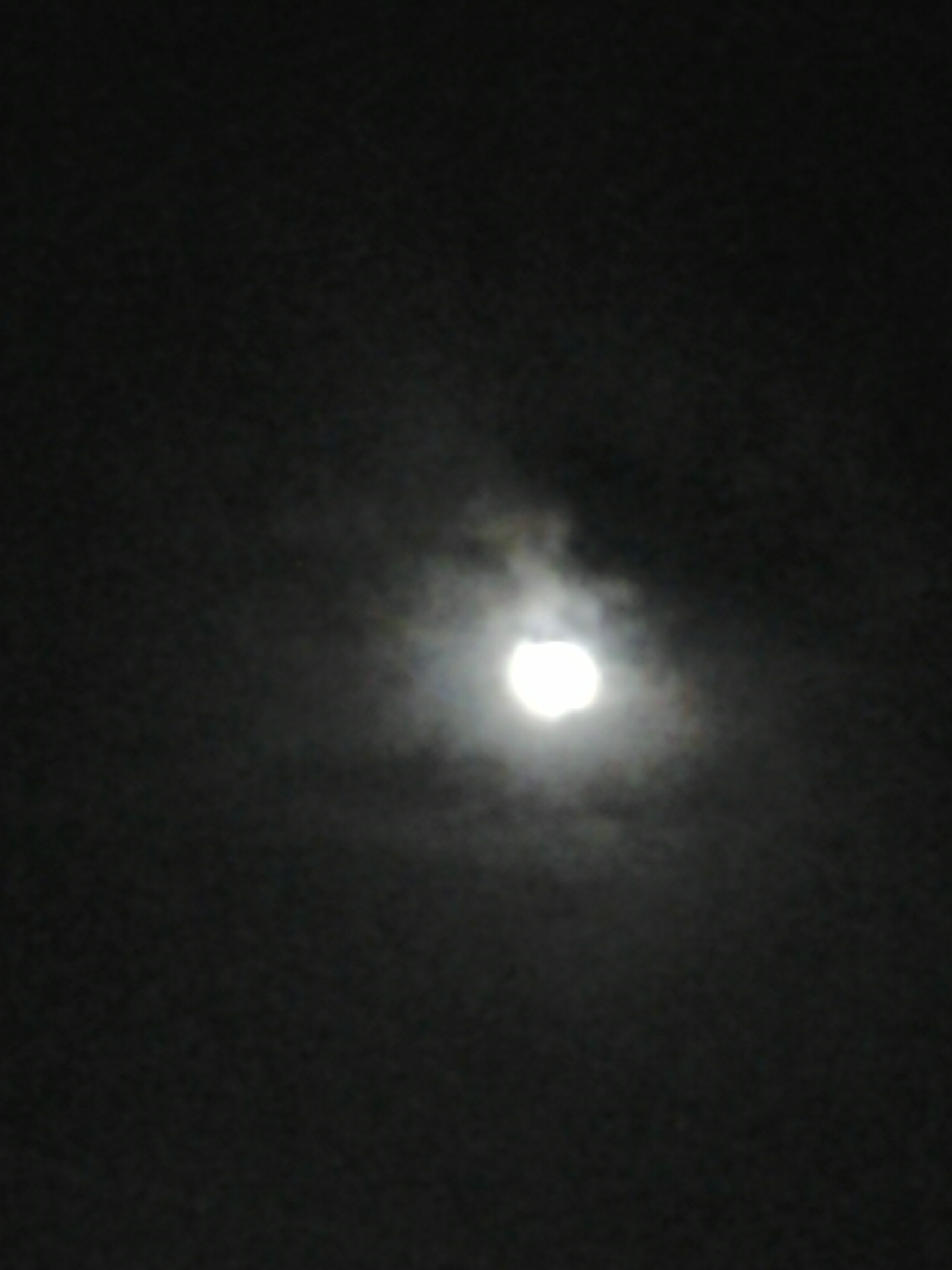 Blurry moon in a cloudy night sky.