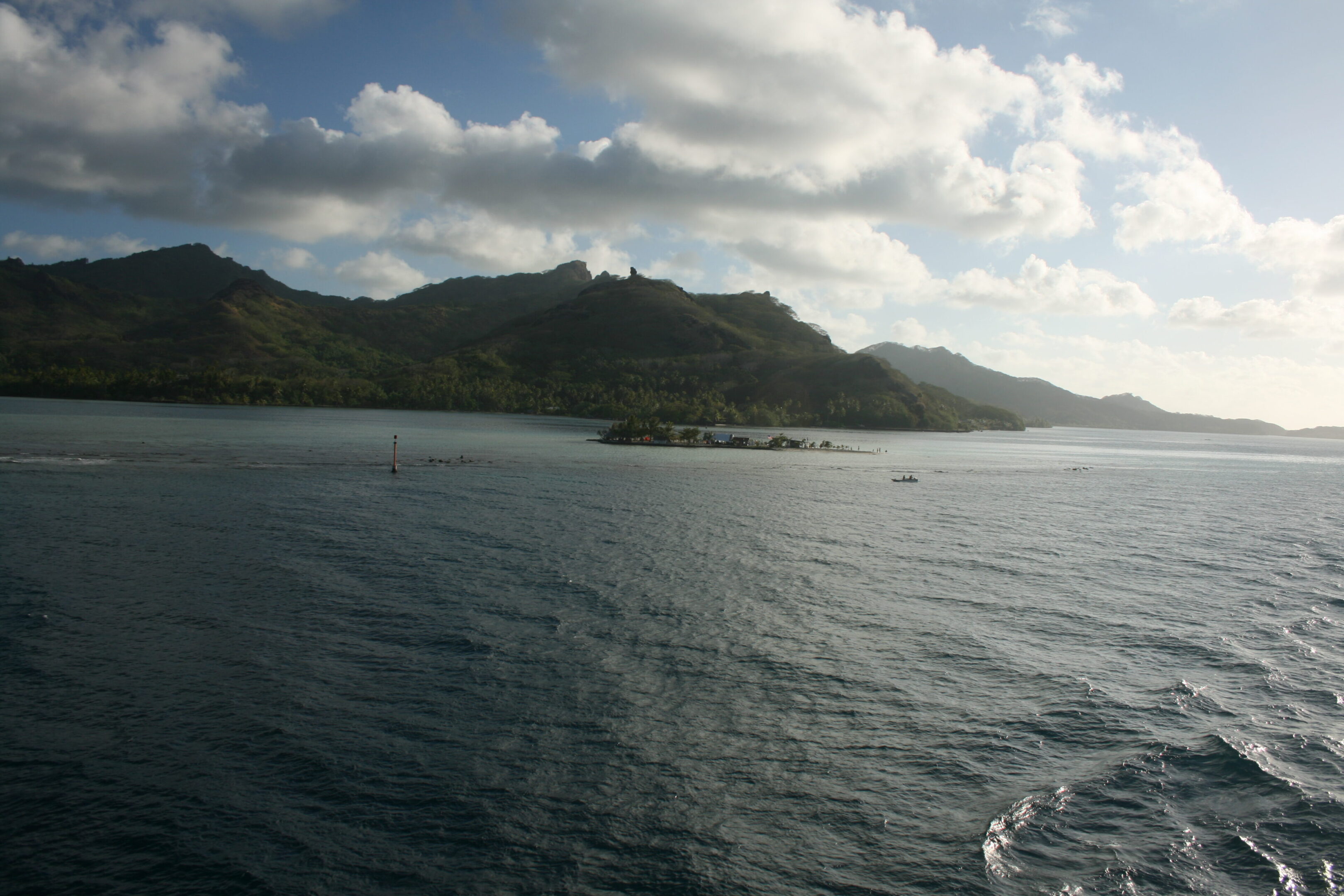 Tropical island with mountains and cloudy sky.