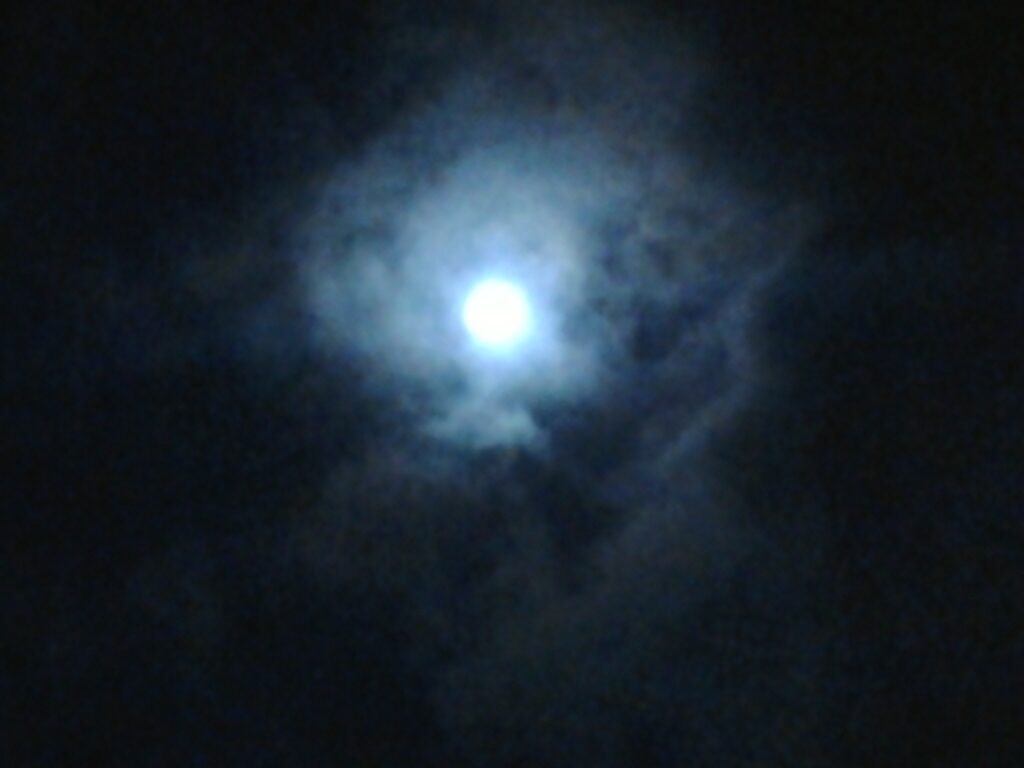 Bright moon surrounded by dark, cloudy sky.
