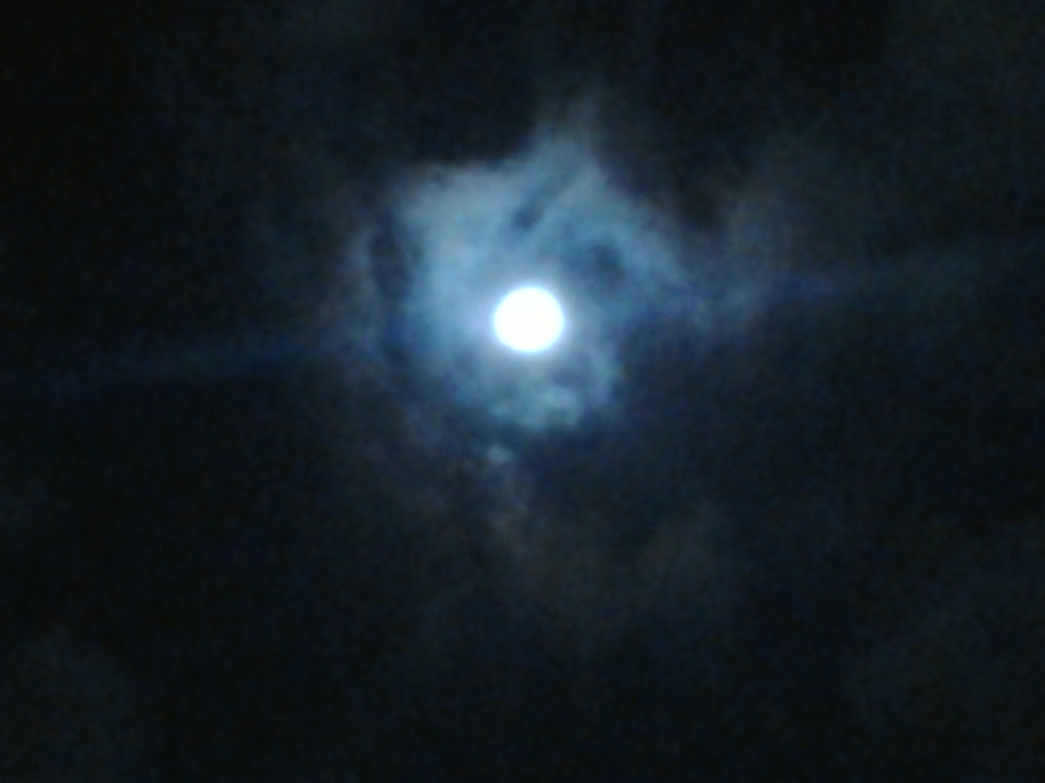 Moon shining through dark, cloudy night sky.