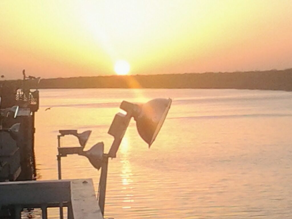 Sunset over calm water with dock.
