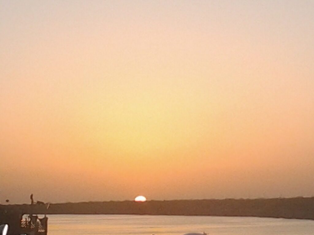 Sunset over calm water and distant horizon.