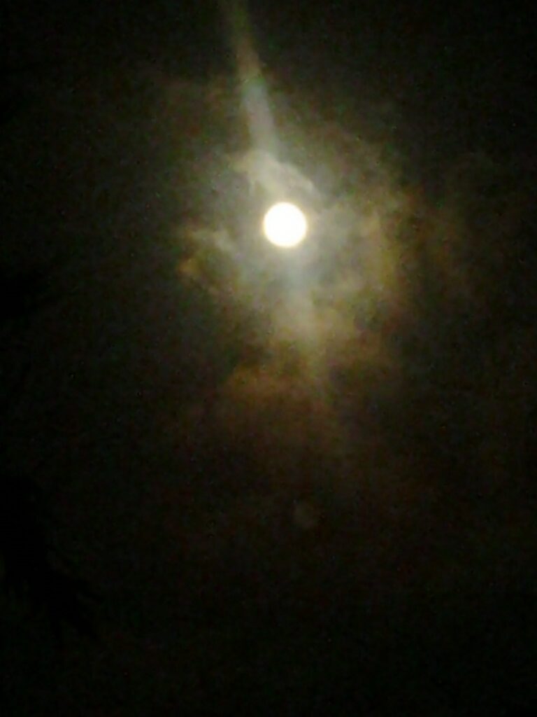 Full moon surrounded by clouds at night.