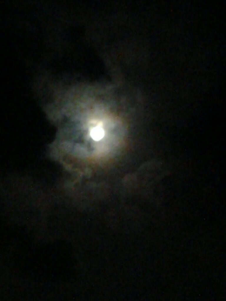 Cloudy night sky with a glowing moon.