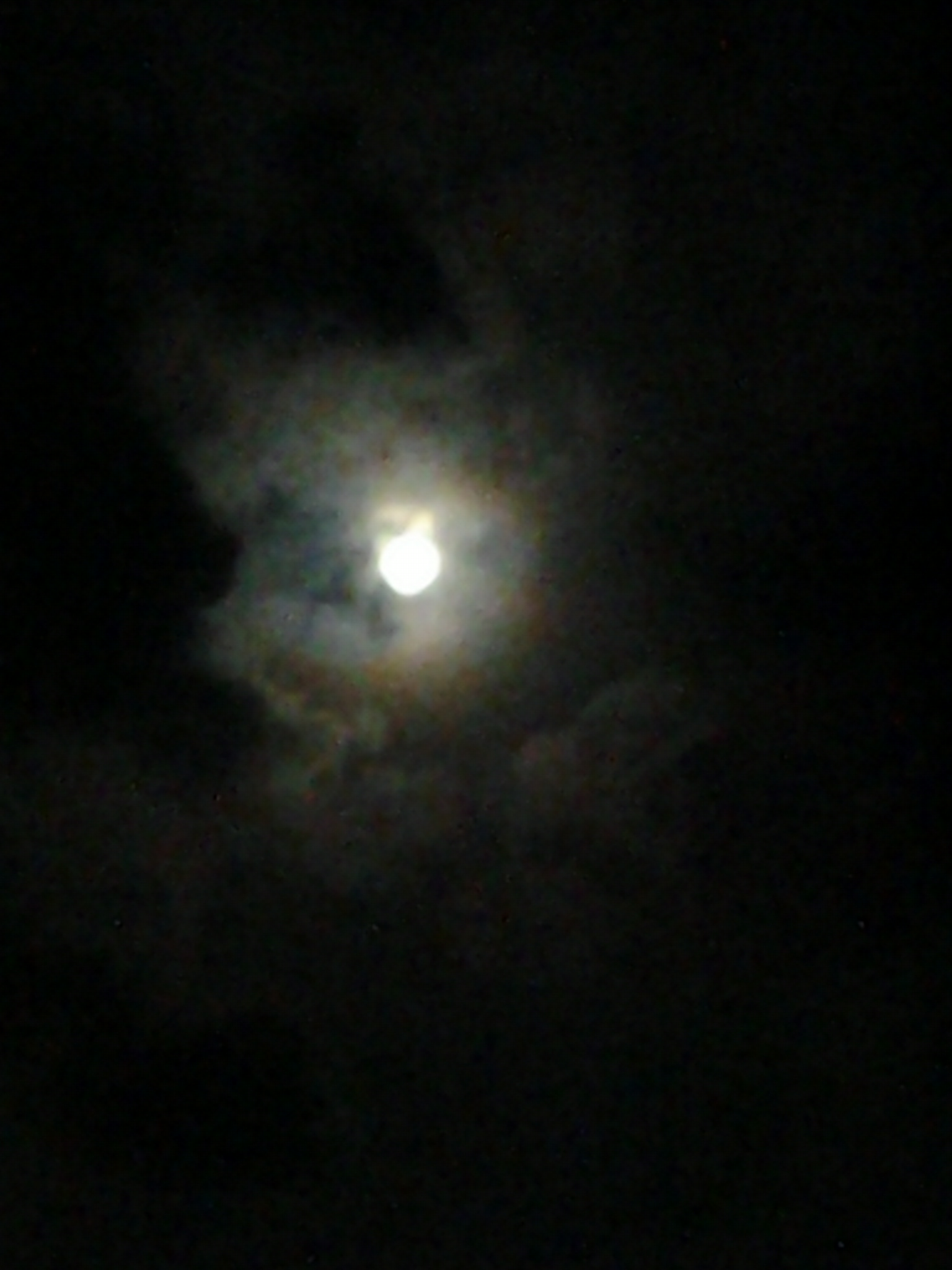 Cloudy night sky with a glowing moon.