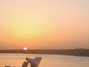 Sunset over calm water and horizon.