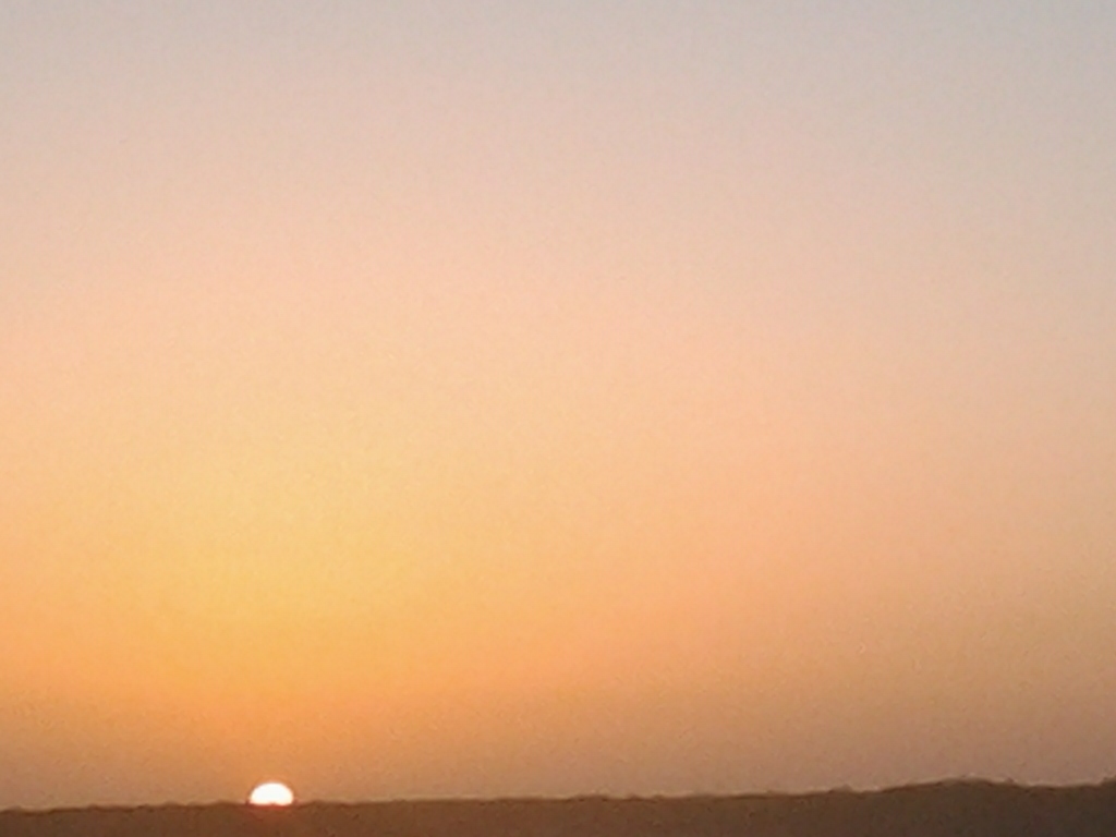 Sunset over a distant, dark horizon.