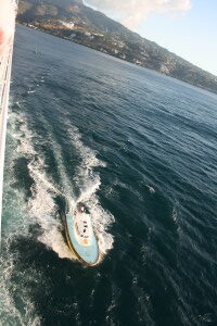 Boat speeding on ocean near coastline.