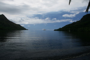 Calm sea with distant boat and hills.