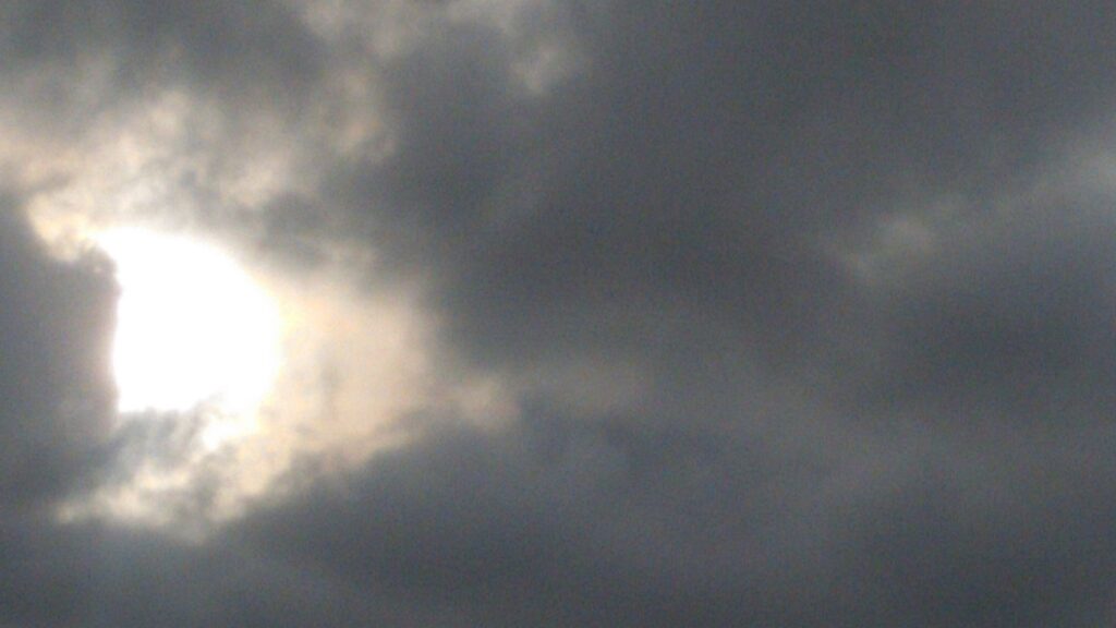 Cloudy sky with sun partially visible.