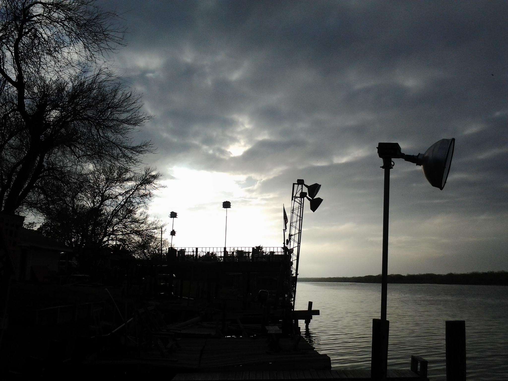 Silhouetted dock and trees at sunset.