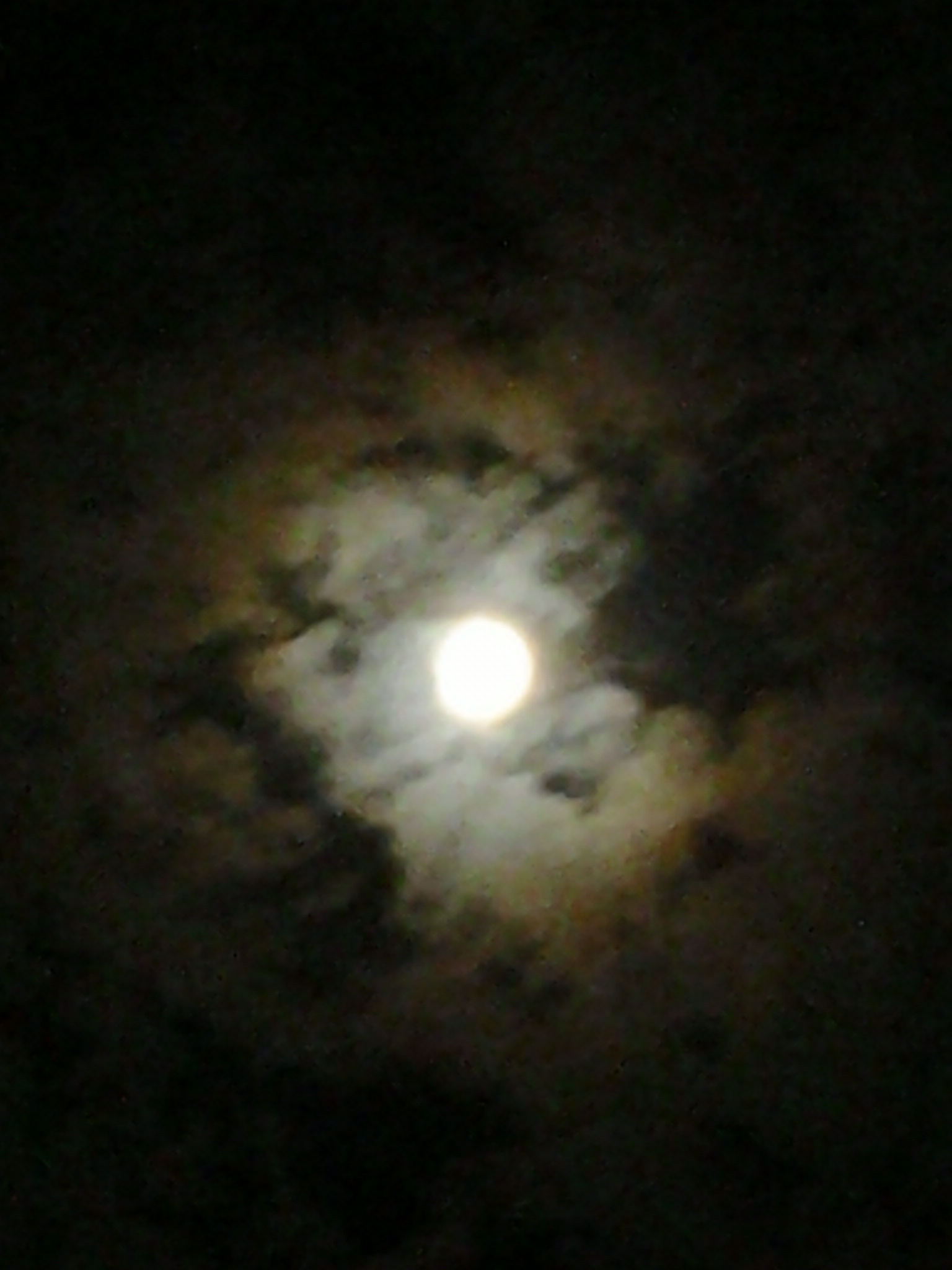 Bright moon surrounded by dark, cloudy sky.