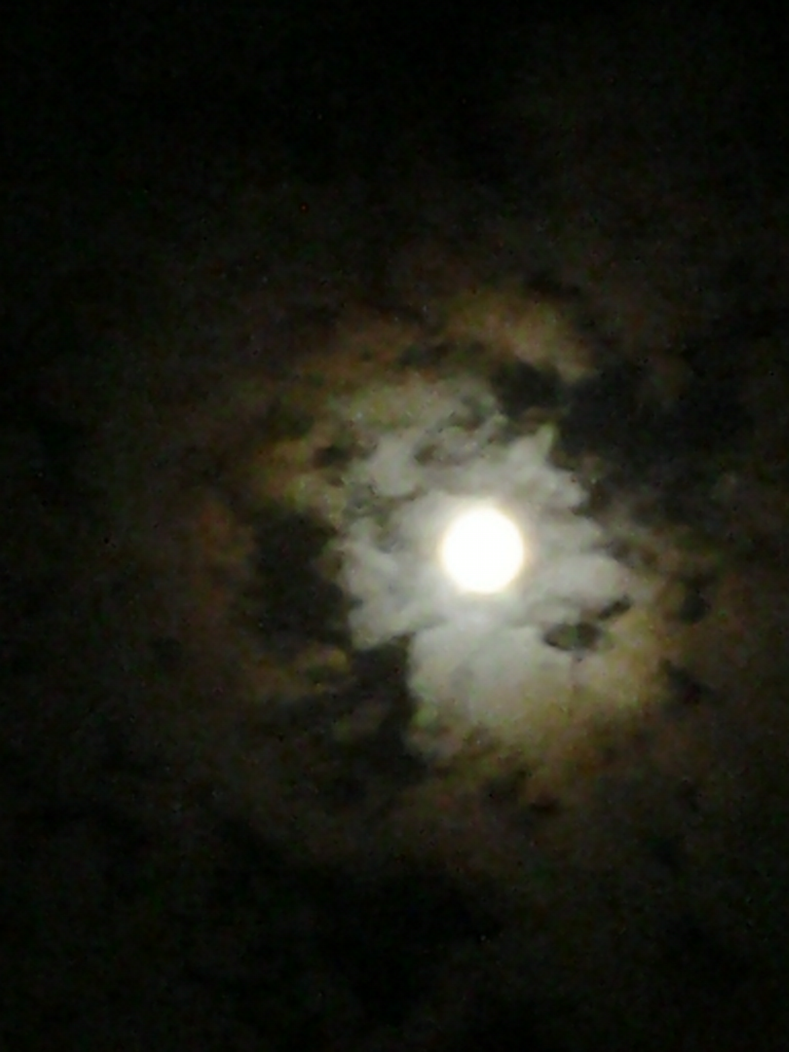 Moon surrounded by dark, cloudy sky.