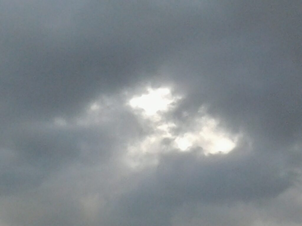 Cloudy sky with sunlight peeking through.