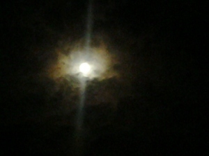 Moon shining through dark, cloudy night sky.