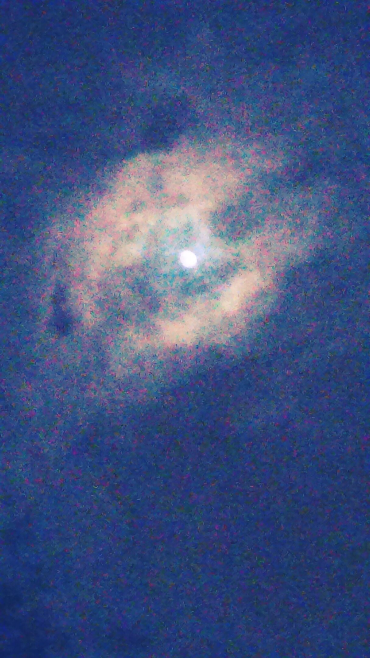Moon surrounded by clouds in night sky.