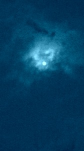 Moon obscured by cloudy night sky.