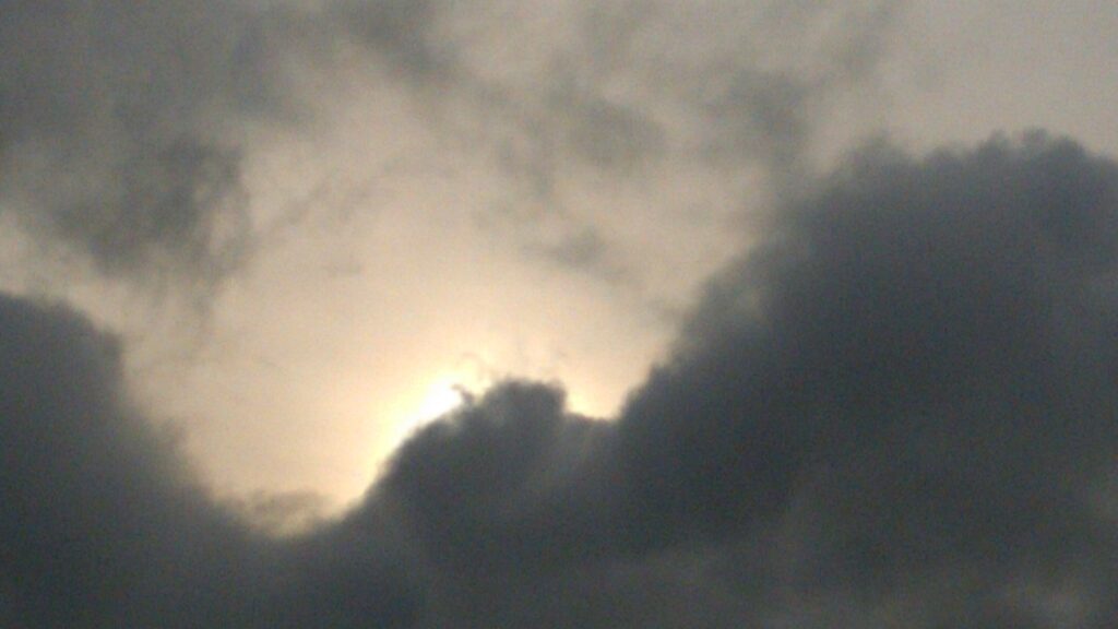 Cloudy sky with sunlight peeking through.