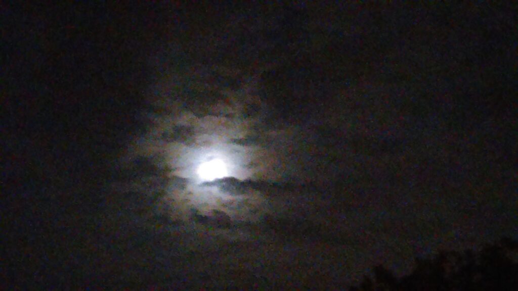 Moon shining through cloudy night sky.