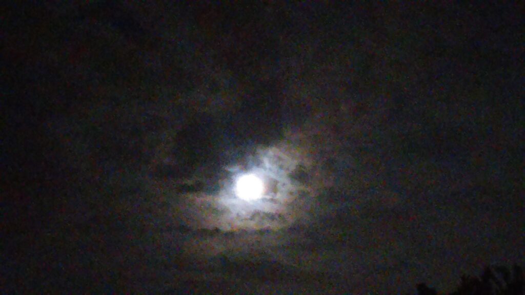 Moon shining through cloudy night sky.