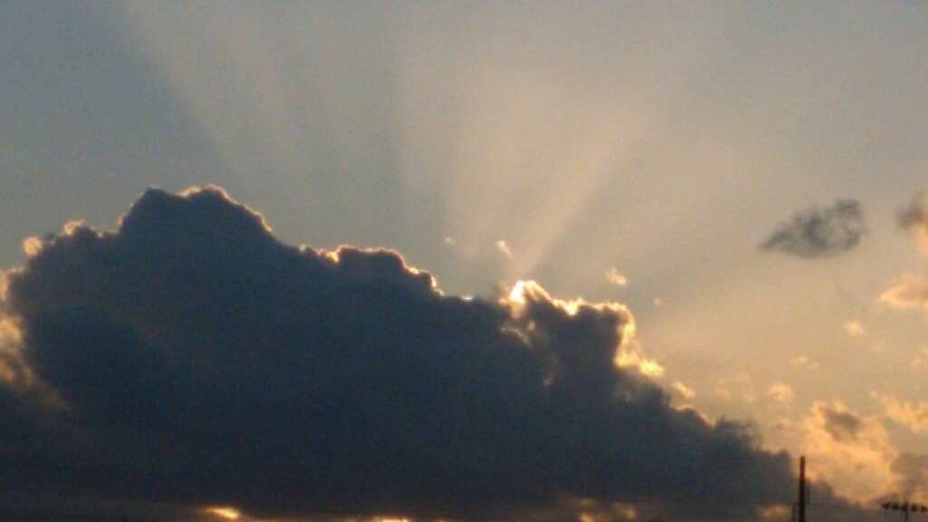 Sun rays emerging from behind dark clouds.