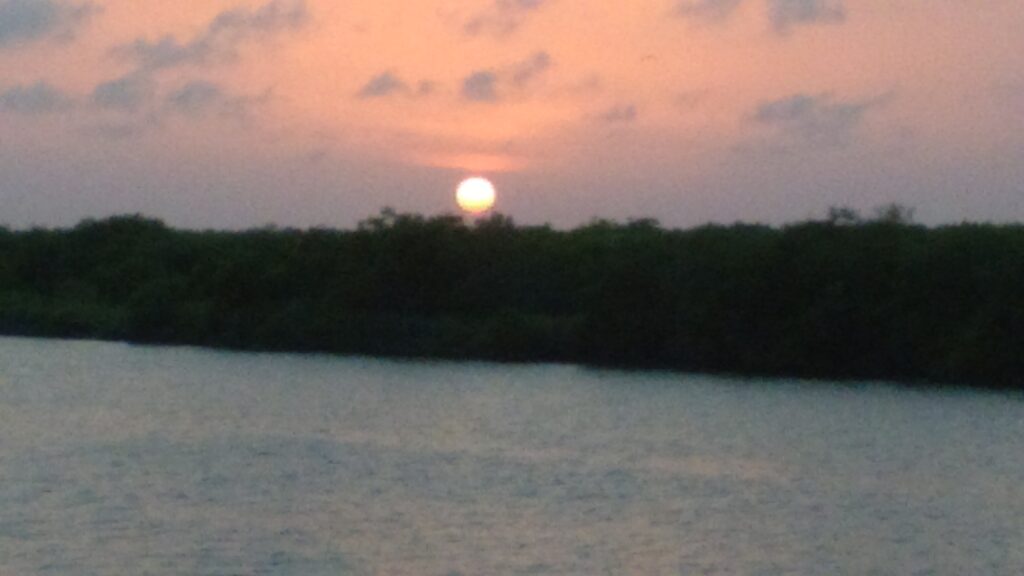 Sunset over calm water with clouds.