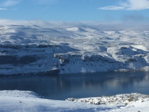 Snowy mountains and lake under blue sky.
