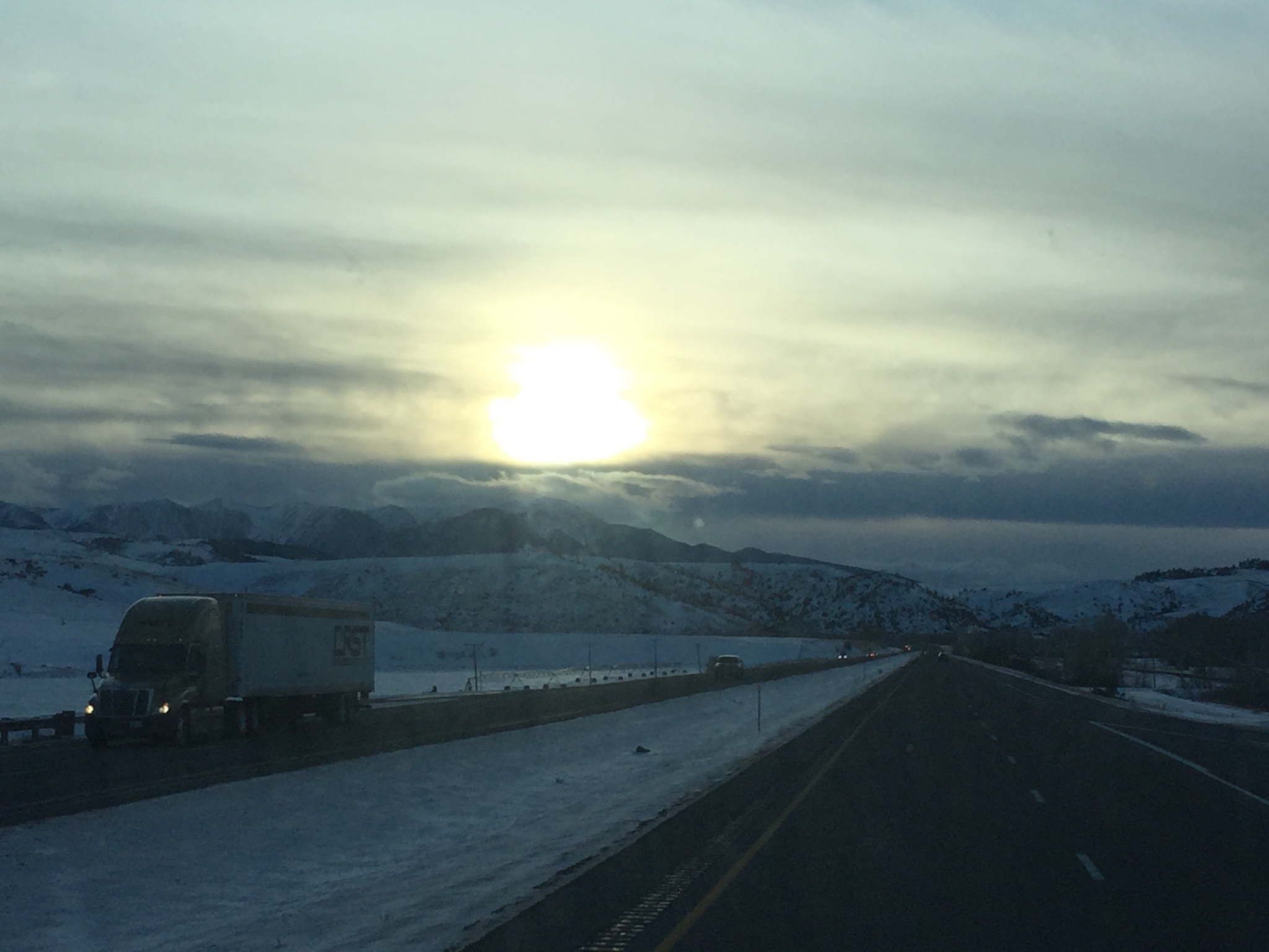 Sunset over snowy highway with truck.