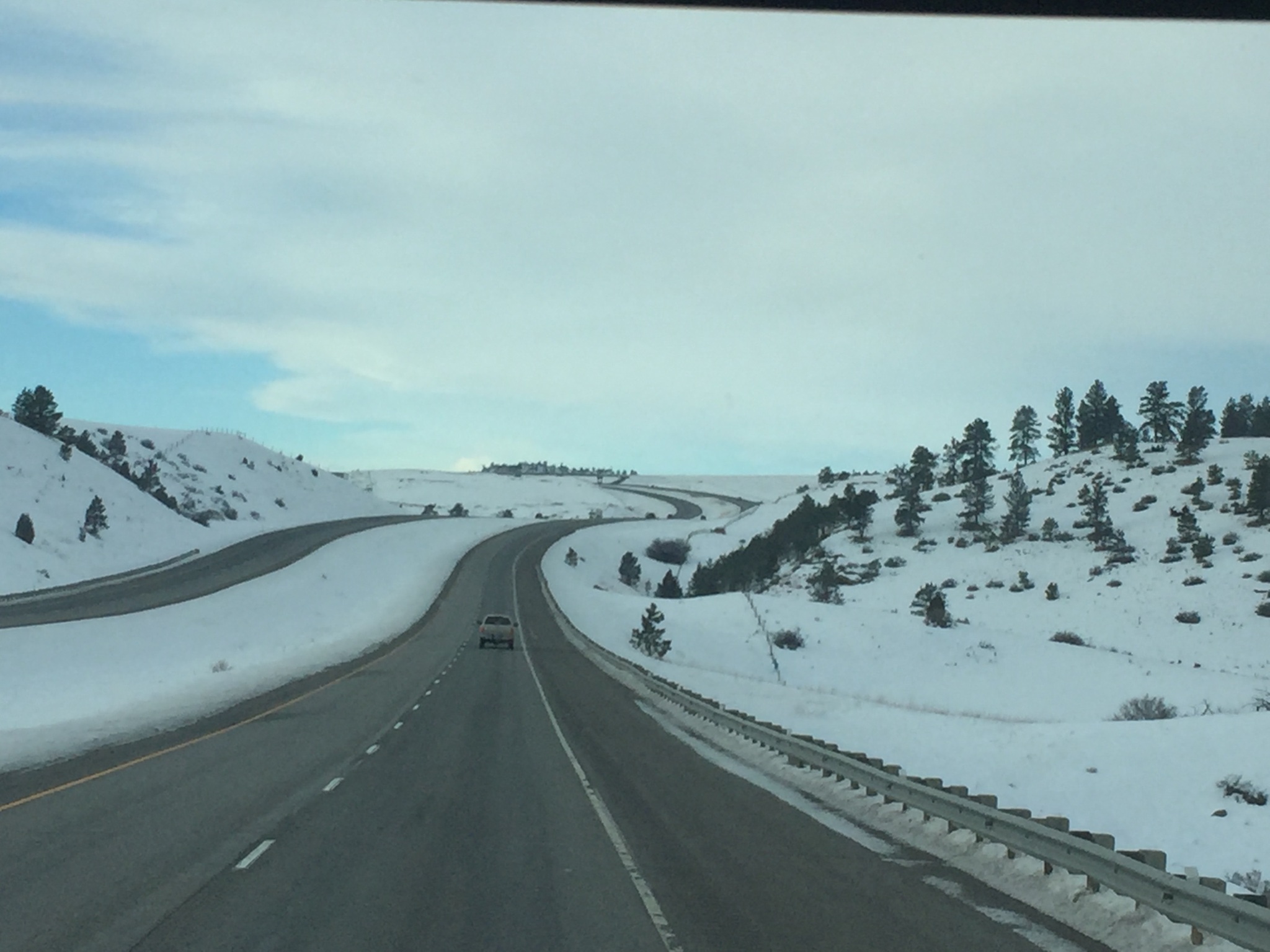 Snowy highway winding through hilly landscape.