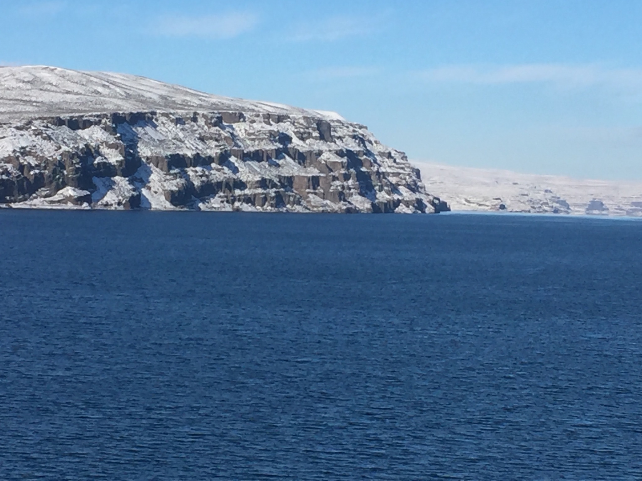Snowy cliffs beside a calm blue sea.