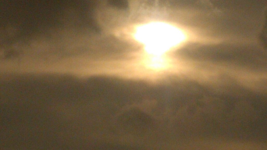 Bright sun shining through cloudy sky.