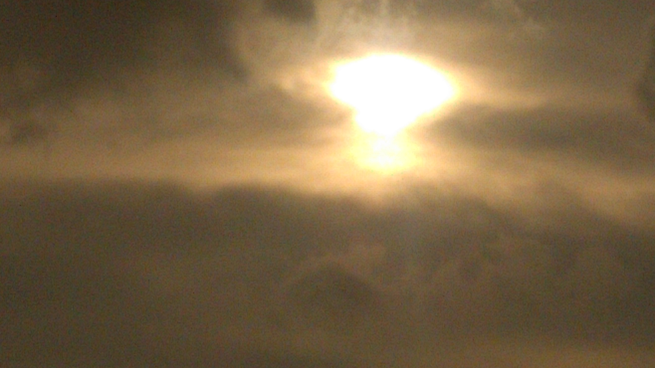 Bright sun shining through cloudy sky.