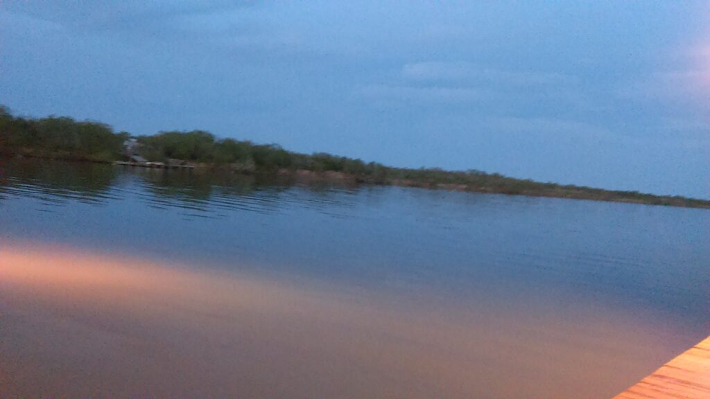 Calm lake at dusk with cloudy sky.