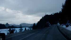 Mountain road with snow and cloudy sky.