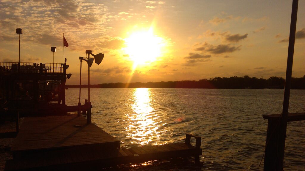 Sunset over calm lake with dock.